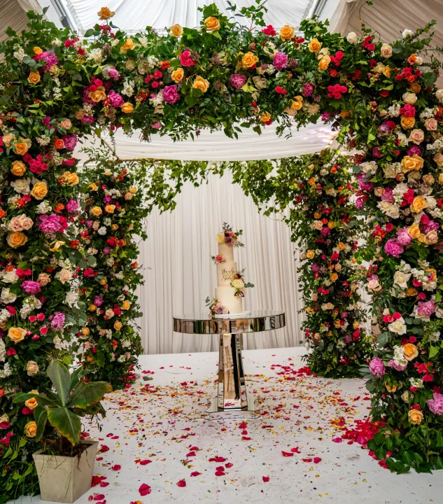 Wedding cake framed by a colourful floral arch