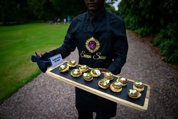 Server presenting a tray of savoury tartlets