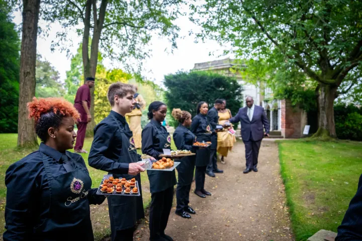 Catering team welcoming guests with canapés in the garden
