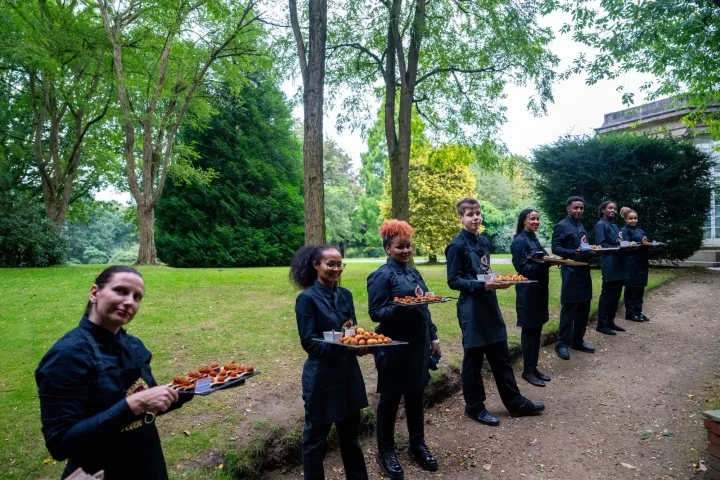 Servers lined up for an outdoor canapé reception