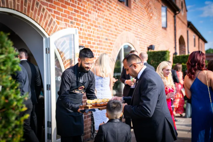 Guests being welcomed with food outside a brick venue