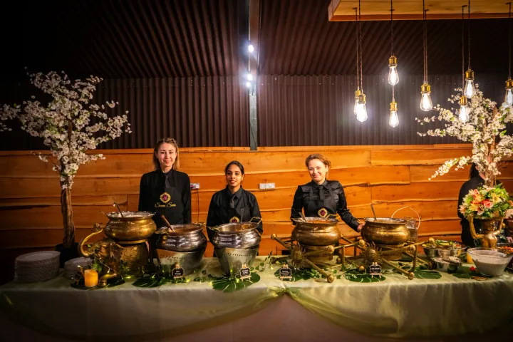 Three servers behind a decorated buffet table