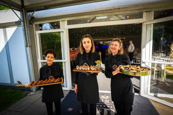 Catering team presenting canapés beside a glass doorway