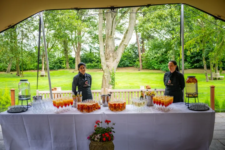 Welcome drinks and servers beneath a garden canopy