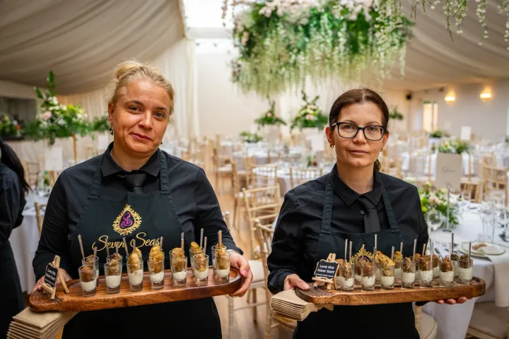 Two servers carrying individual canapé glasses