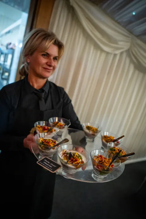 Server carrying individual starter bowls in a marquee