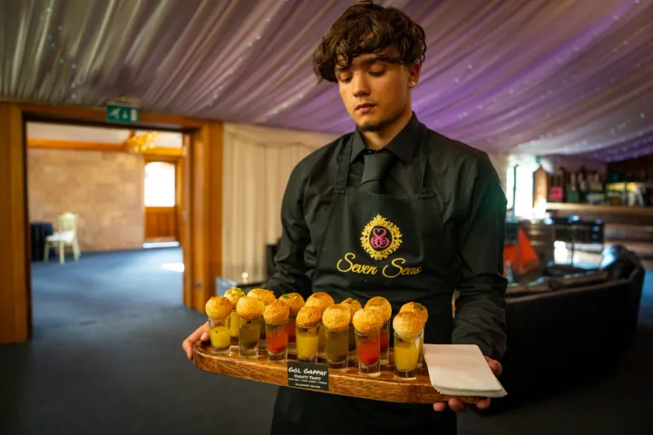 Server presenting gol gappay with colourful pani