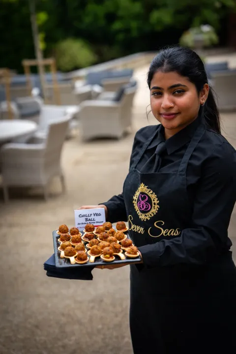Server presenting bite-sized canapés outdoors