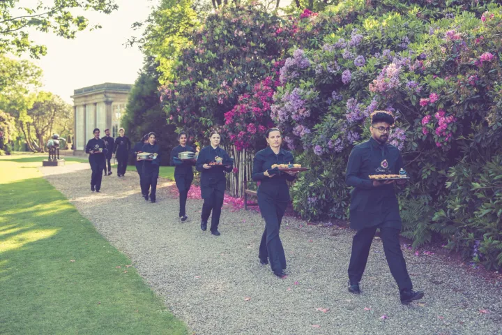 Servers walking through the garden with canapé trays
