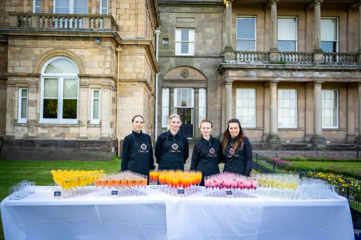 Welcome drinks and servers outside a stately house