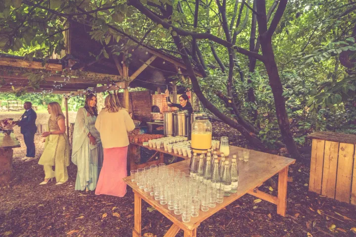 An outdoor drinks reception beneath leafy trees