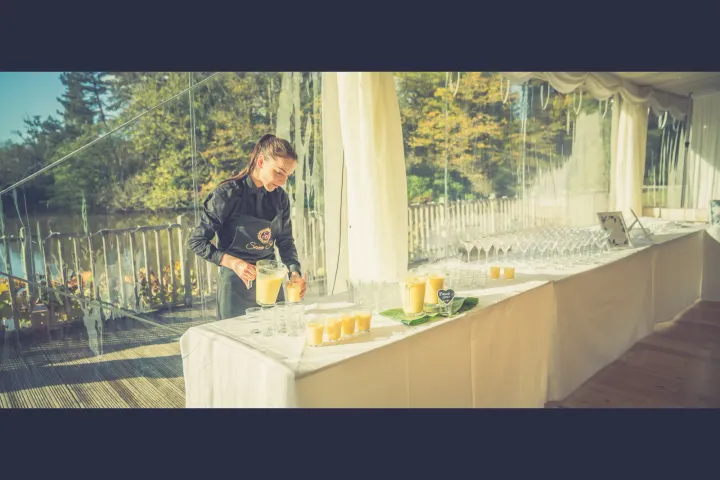 Server preparing a drinks table beside tall windows