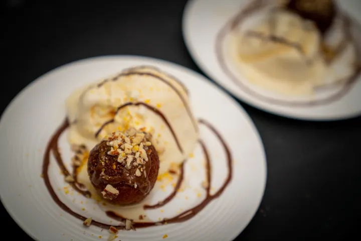 A plated dessert with ice cream and chocolate sauce