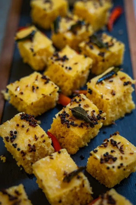 Yellow dhokla topped with herbs and seeds