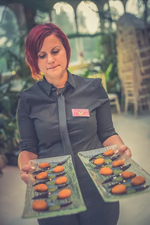 Server carrying trays of small burger canapés
