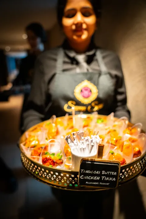 Server carrying individual glasses of savoury bites