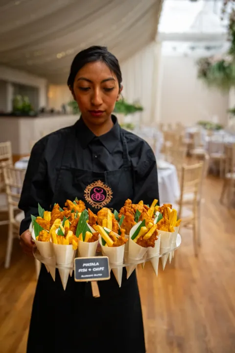 Server presenting savoury cones in a marquee