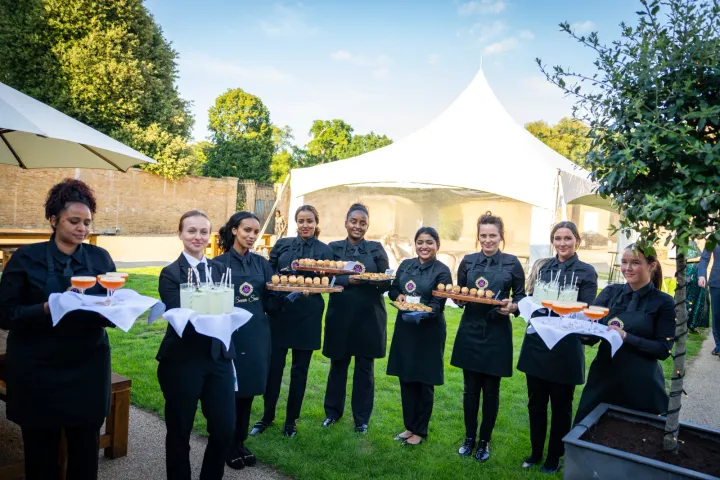 Canapé service on a lawn beside a white marquee