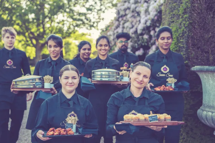 Catering team gathered with serving trays on garden steps