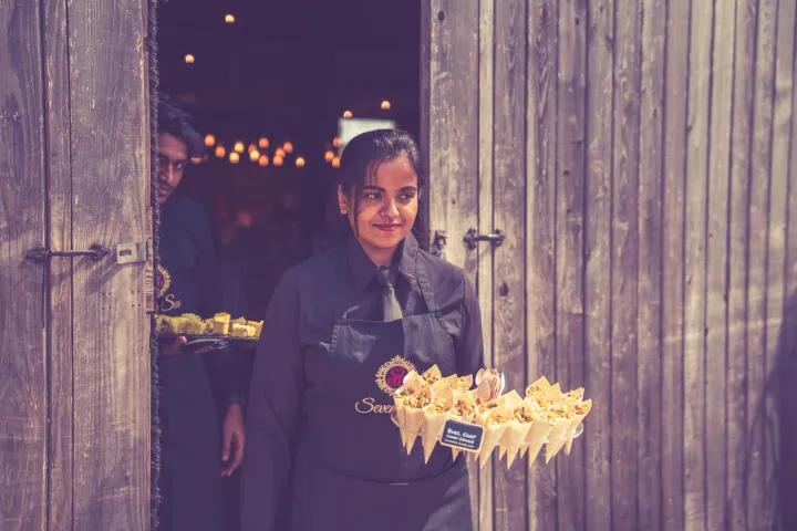 Server carrying savoury cones beside a stone doorway