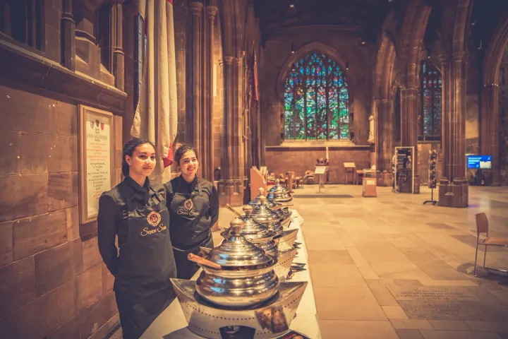 Catering team beside buffet dishes in a historic hall