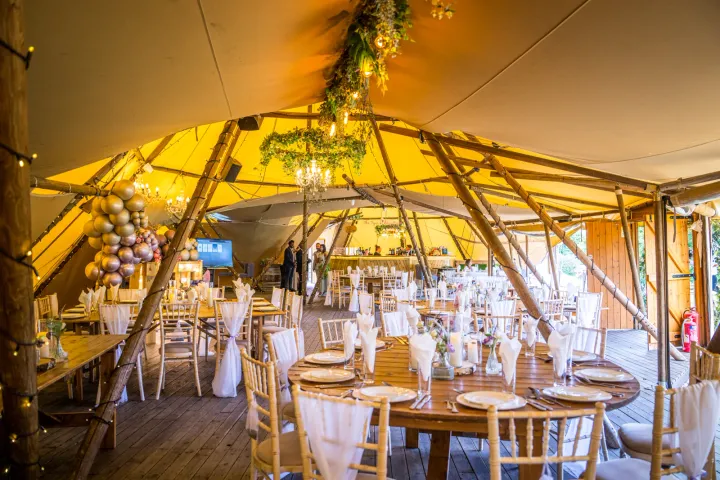 Reception tables inside a timber-framed tent