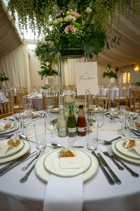 A white table setting beneath hanging greenery