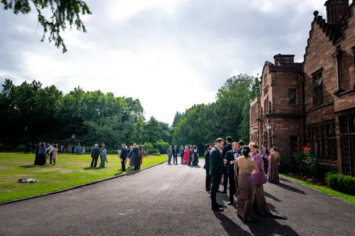 Guests arriving beside a brick manor house