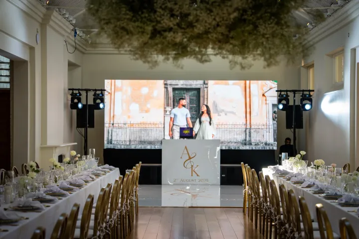 Long dining tables facing a white DJ booth
