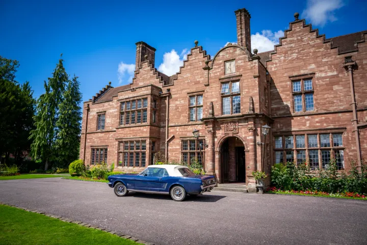Brick manor house with a vintage car outside