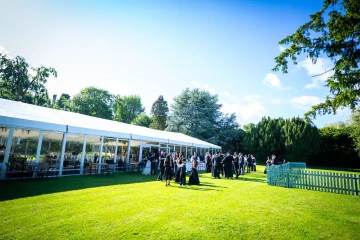 A long marquee beside a sunlit lawn