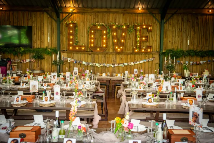 Rustic reception tables beneath illuminated LOVE letters