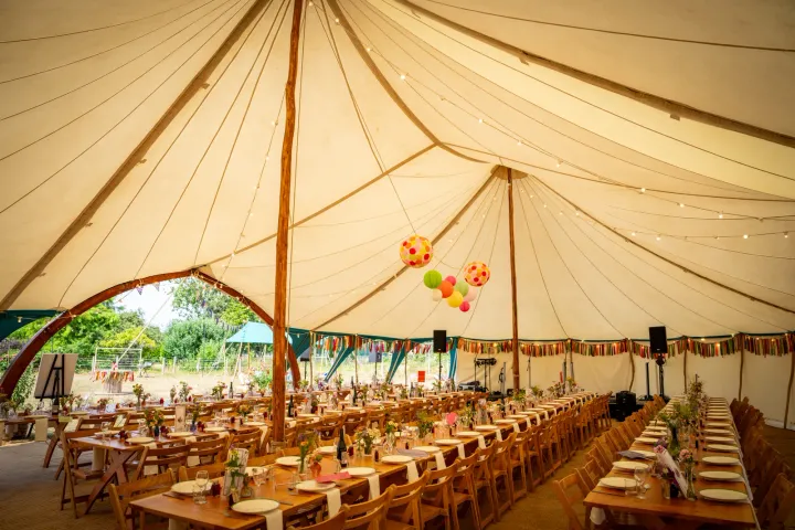 Long banquet tables inside a sailcloth tent