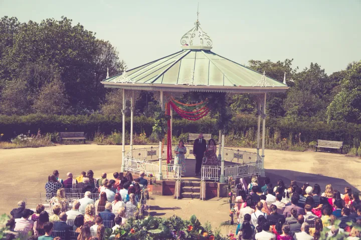 Guests seated beside a garden ceremony gazebo