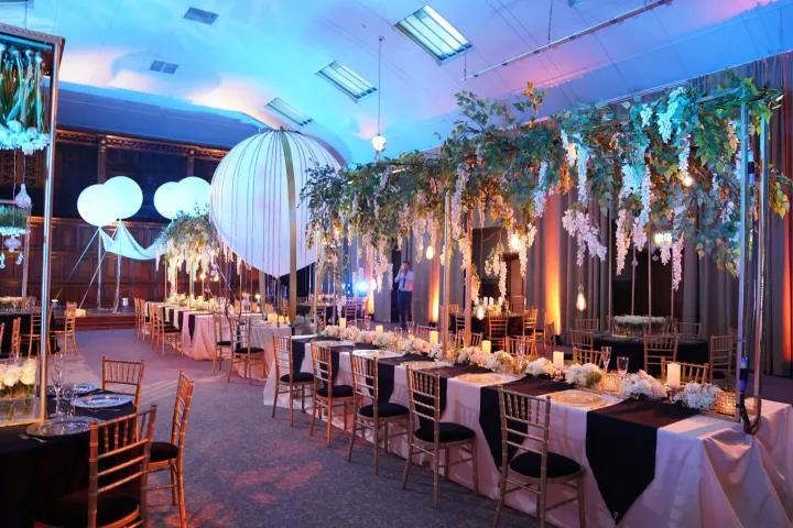 Banquet tables beneath greenery and white lanterns