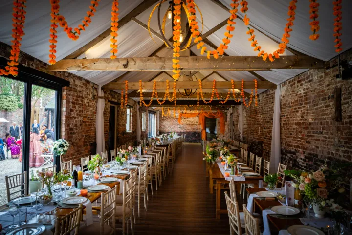 Long dining tables beneath orange floral garlands