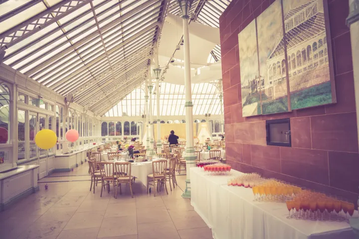 Dining tables and drinks in a bright glasshouse