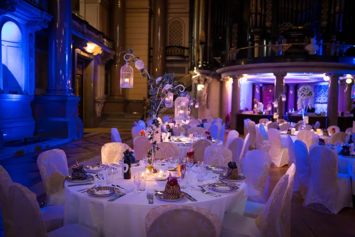 Dressed reception tables beneath blue uplighting